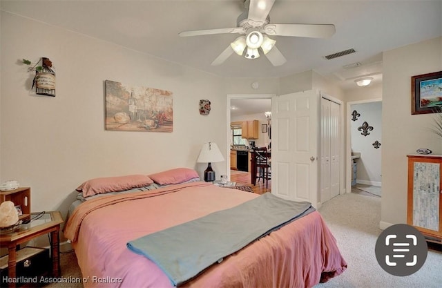 bedroom with ceiling fan, light colored carpet, connected bathroom, and a closet