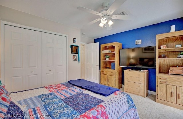 bedroom with ceiling fan, light carpet, and a closet