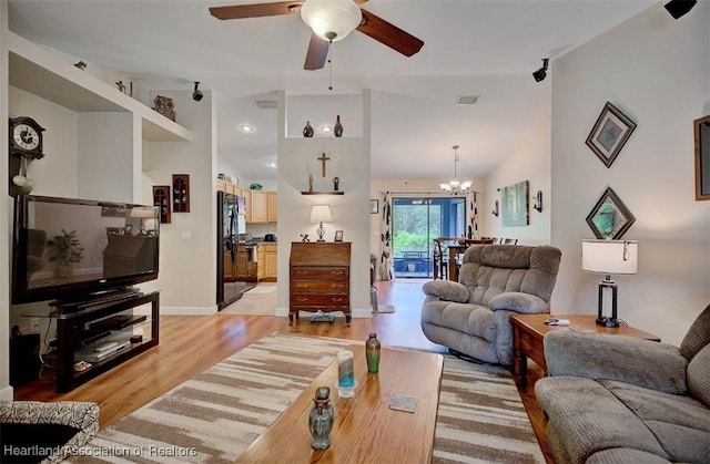 living room with vaulted ceiling, ceiling fan with notable chandelier, and light wood-type flooring