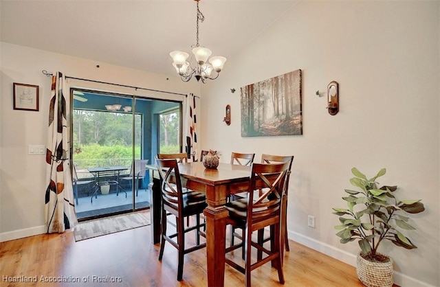 dining area featuring a chandelier, light hardwood / wood-style flooring, and lofted ceiling