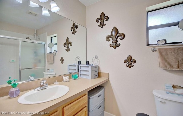 bathroom with vanity, toilet, and a shower with door