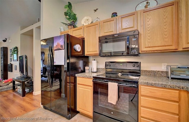 kitchen featuring black appliances, light stone countertops, light tile patterned floors, and light brown cabinetry