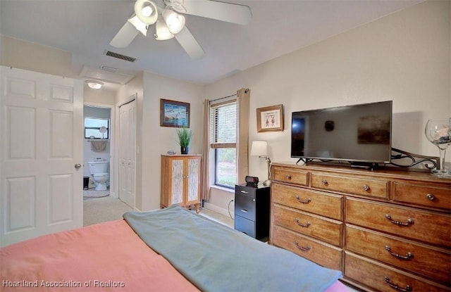 bedroom with ceiling fan, a closet, light colored carpet, and ensuite bath