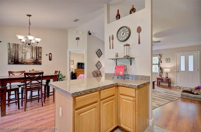 kitchen with kitchen peninsula, light brown cabinets, ceiling fan with notable chandelier, and light hardwood / wood-style flooring