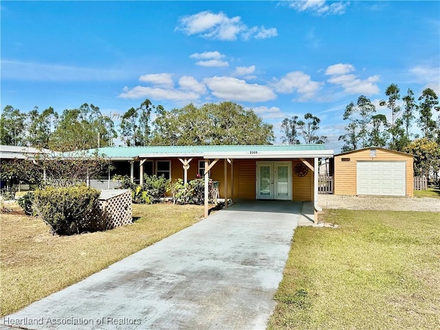 view of front of home with a garage, an outdoor structure, a front yard, and french doors