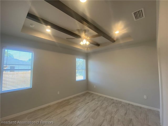 spare room featuring a raised ceiling and ceiling fan