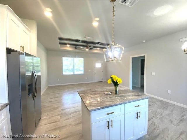 kitchen featuring decorative light fixtures, dark stone countertops, white cabinets, stainless steel fridge with ice dispenser, and a kitchen island