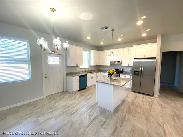 kitchen with sink, a kitchen island, stainless steel appliances, and decorative light fixtures