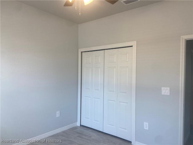 unfurnished bedroom featuring ceiling fan, a closet, and hardwood / wood-style floors