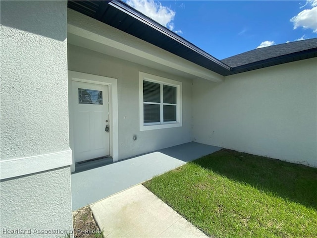 view of exterior entry featuring a lawn