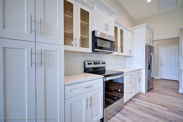 kitchen featuring visible vents, light stone countertops, white cabinets, tasteful backsplash, and stainless steel appliances