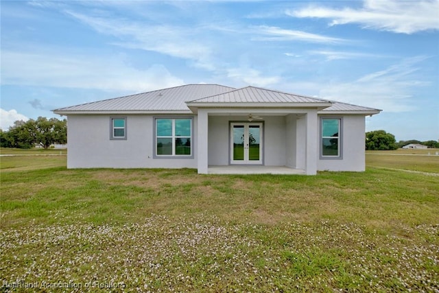rear view of house with french doors, a patio, stucco siding, and a yard