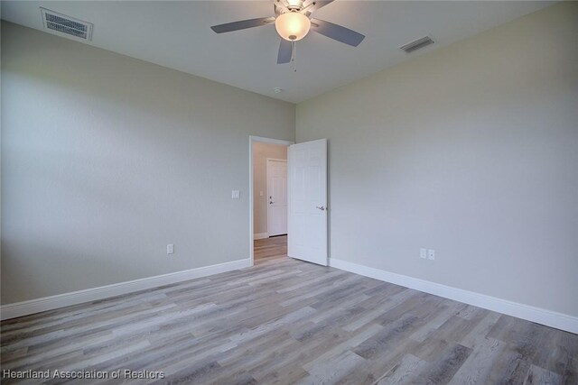 empty room featuring a ceiling fan, baseboards, visible vents, and light wood-style flooring