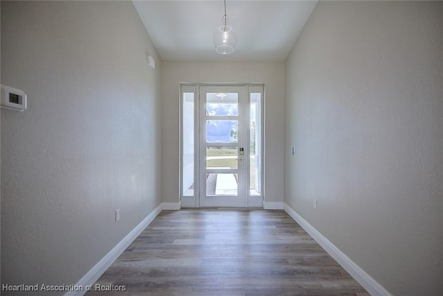doorway to outside featuring baseboards and wood finished floors