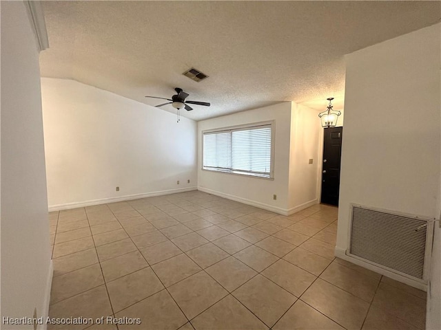 unfurnished room with a textured ceiling, light tile patterned floors, visible vents, and a ceiling fan