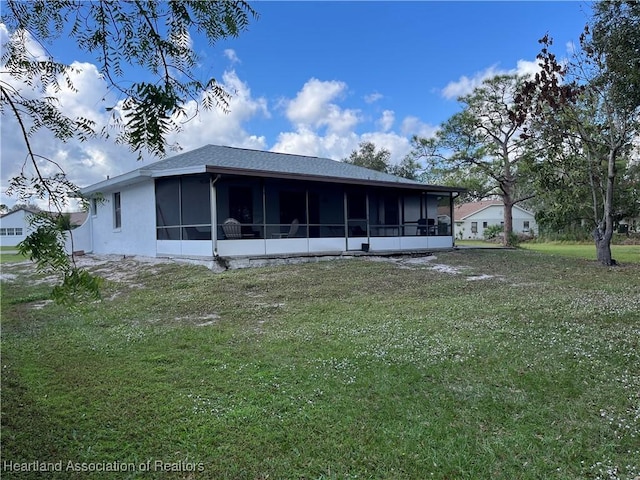 rear view of property featuring a yard and a sunroom