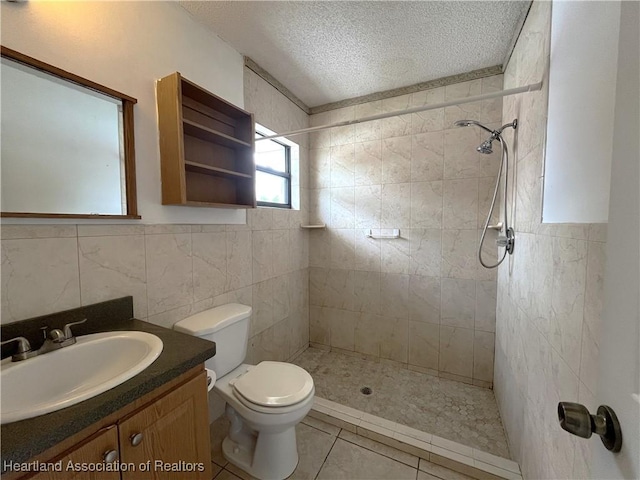 full bathroom featuring toilet, a textured ceiling, vanity, tile patterned flooring, and tiled shower