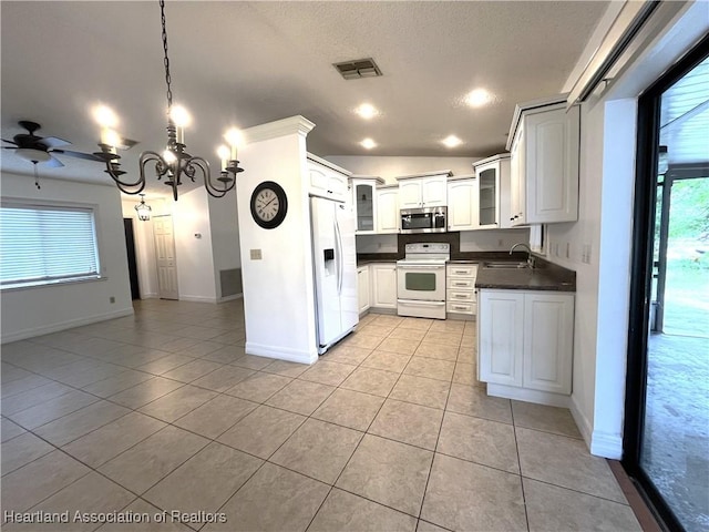 kitchen with white appliances, white cabinets, dark countertops, glass insert cabinets, and a sink