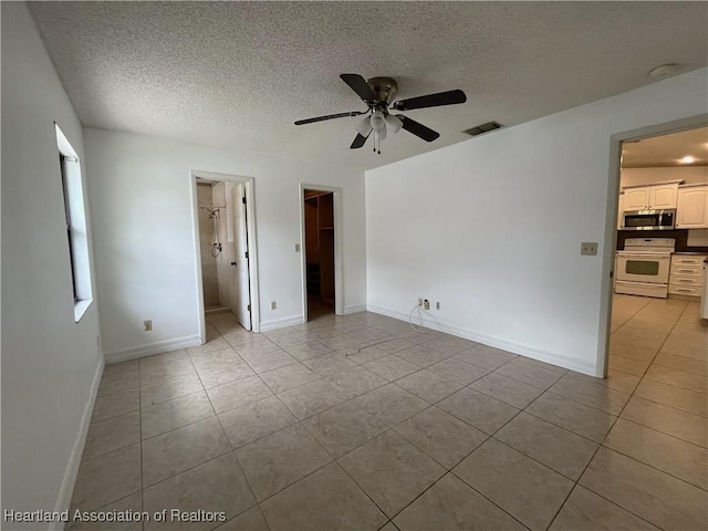 interior space featuring visible vents, a textured ceiling, baseboards, and light tile patterned floors