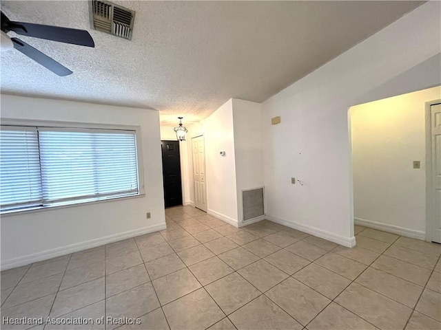 empty room featuring visible vents, ceiling fan, a textured ceiling, and light tile patterned floors