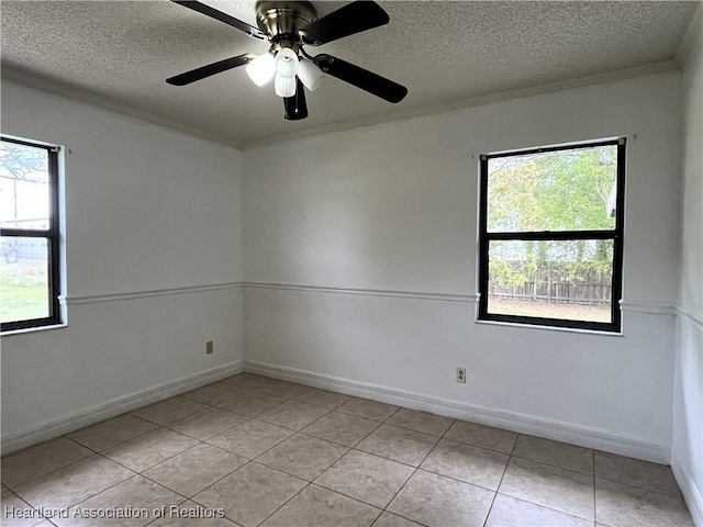 spare room with crown molding, a textured ceiling, baseboards, and light tile patterned floors