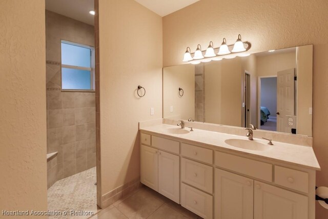 bathroom with tile patterned flooring, vanity, and tiled shower