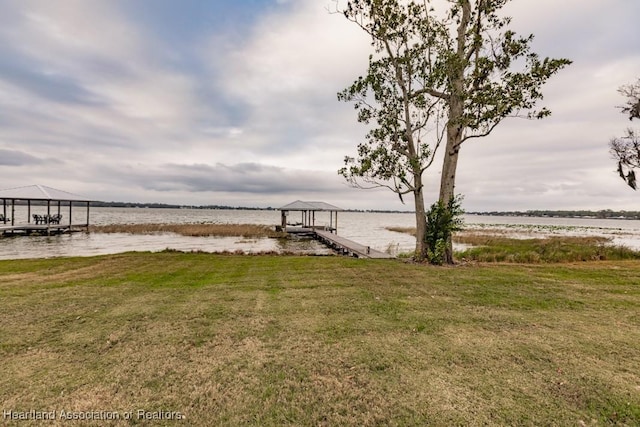 view of dock with a lawn and a water view