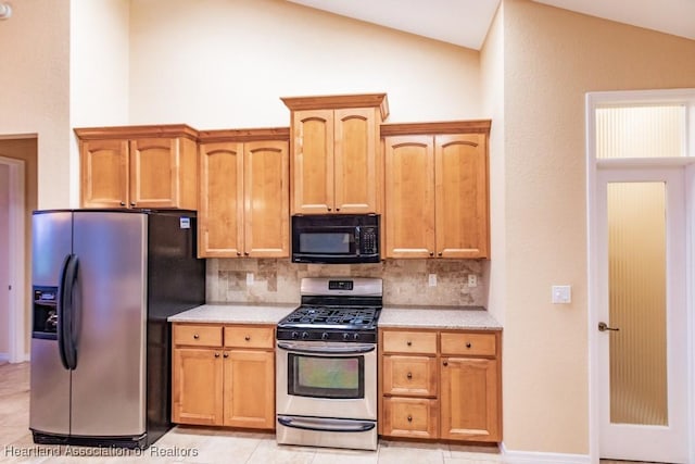 kitchen featuring light tile patterned floors, stainless steel appliances, tasteful backsplash, and lofted ceiling