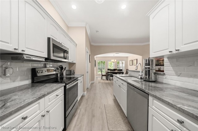2036 Ashley Oaks Cir, Sebring, FL 33870 - kitchen featuring appliances with stainless steel finishes, a sink, arched walkways, tasteful backsplash, and ornamental molding
