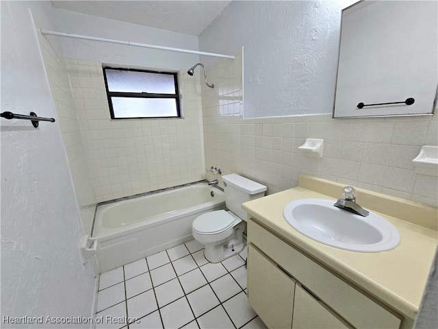 full bathroom with toilet, tiled shower / bath, tile walls, vanity, and tile patterned flooring