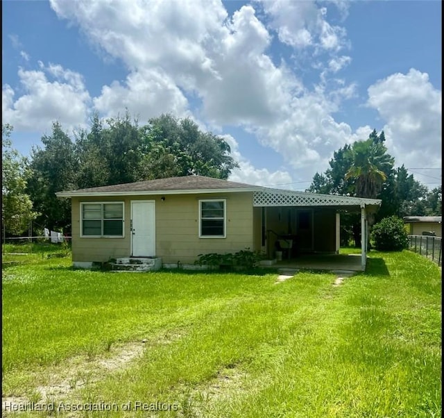 rear view of house with a carport and a yard