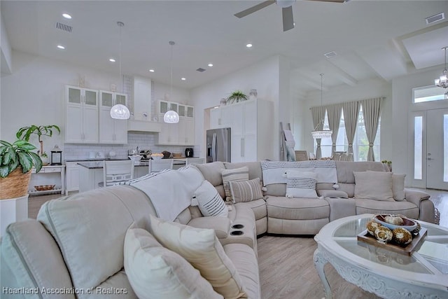 living room featuring ceiling fan, a high ceiling, and light hardwood / wood-style flooring