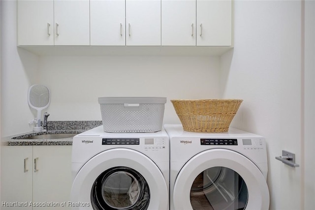 laundry area with washing machine and dryer, cabinets, and sink