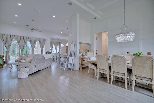 interior space featuring ceiling fan with notable chandelier, a towering ceiling, and light hardwood / wood-style flooring