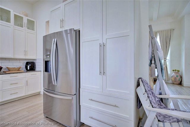 kitchen with white cabinetry, light hardwood / wood-style floors, stainless steel refrigerator with ice dispenser, decorative backsplash, and stone countertops