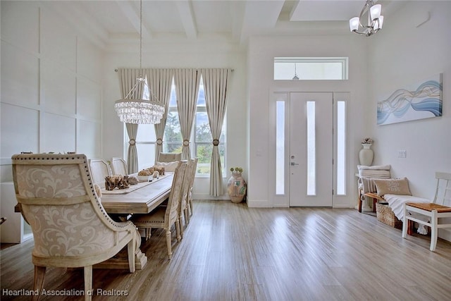 foyer featuring hardwood / wood-style flooring, beam ceiling, and a chandelier