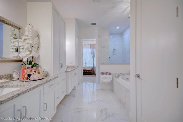 bathroom featuring tiled bath and vanity