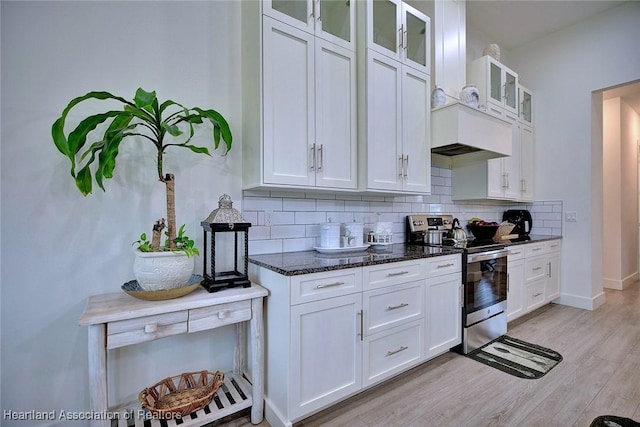 kitchen featuring stainless steel range with electric cooktop, backsplash, white cabinets, and dark stone counters