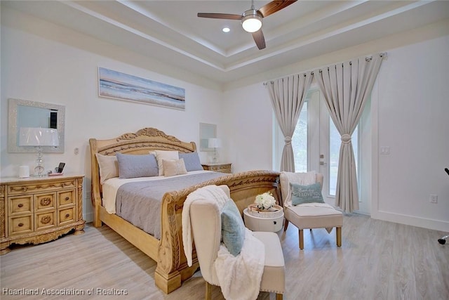 bedroom featuring ceiling fan, french doors, a raised ceiling, and light hardwood / wood-style flooring