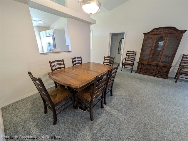 carpeted dining space featuring lofted ceiling