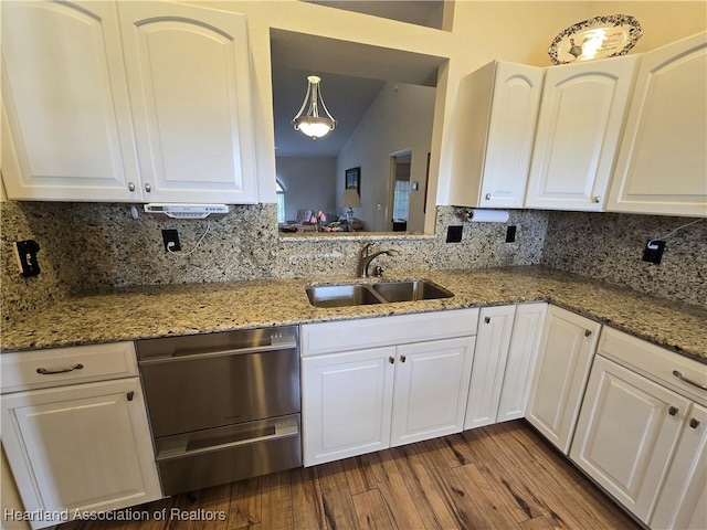 kitchen featuring backsplash, sink, white cabinetry, hanging light fixtures, and lofted ceiling