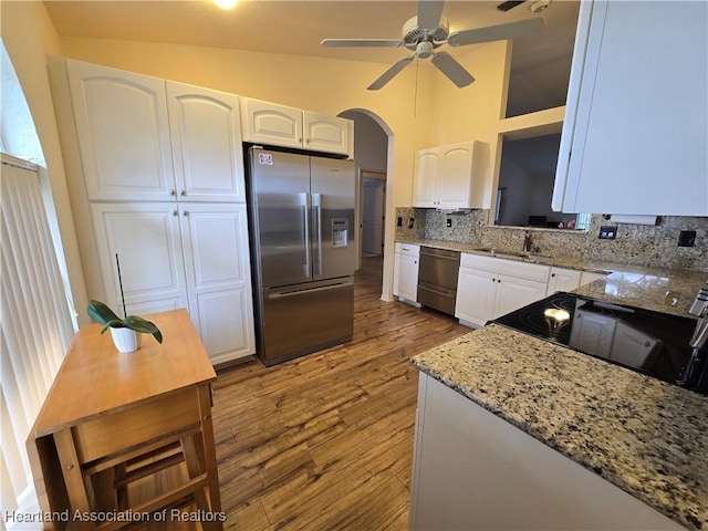 kitchen with lofted ceiling, sink, tasteful backsplash, white cabinetry, and stainless steel appliances