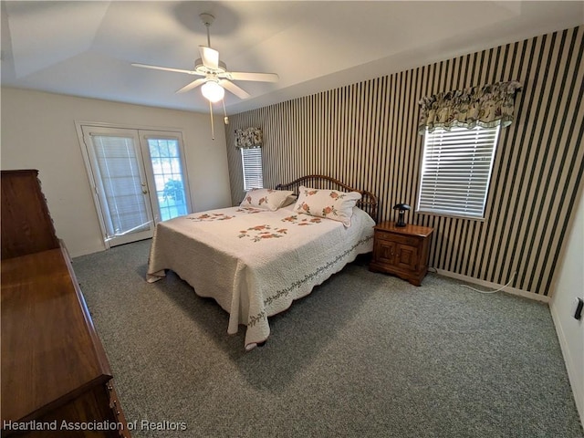 bedroom featuring access to exterior, french doors, a tray ceiling, ceiling fan, and carpet floors