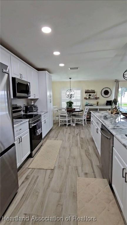 325 Anderson St NE, Lake Placid, FL 33852 - kitchen with appliances with stainless steel finishes, pendant lighting, light stone countertops, light hardwood / wood-style floors, and white cabinets