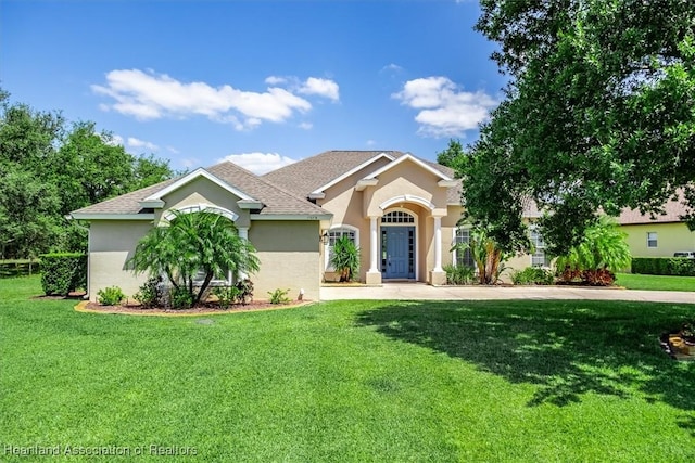 view of front of house featuring a front lawn, a shingled roof, and stucco siding
