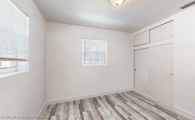 unfurnished bedroom with light wood-type flooring and a closet