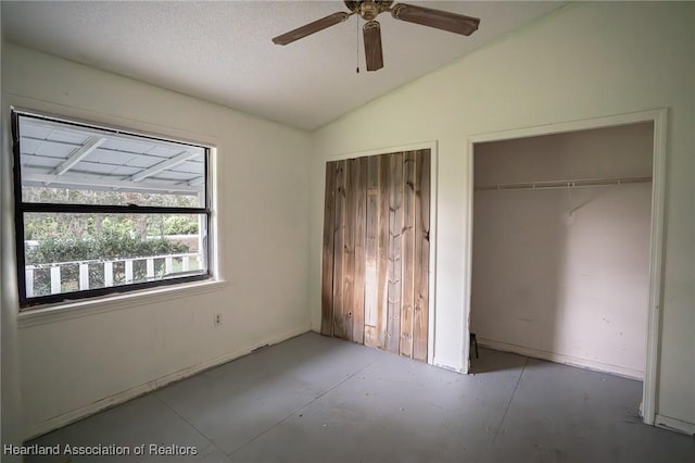 unfurnished bedroom featuring ceiling fan, concrete floors, and vaulted ceiling