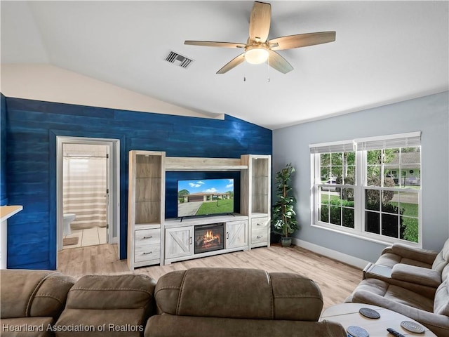 living room with ceiling fan, light hardwood / wood-style floors, a fireplace, and vaulted ceiling