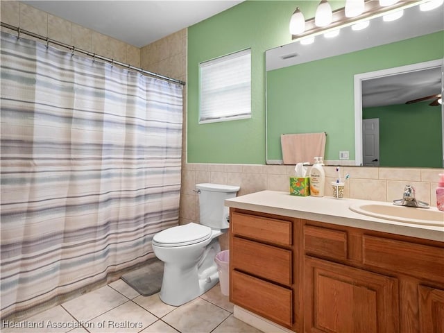 bathroom featuring tile patterned floors, vanity, ceiling fan, tile walls, and toilet