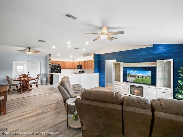 living room with ceiling fan, light hardwood / wood-style floors, and lofted ceiling